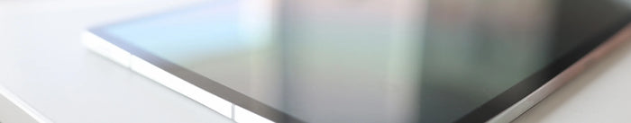 Nahaufnahme eines modernen Tablets mit dunklem, spiegelndem Bildschirm. Das Gerät liegt auf einer hellen Oberfläche und symbolisiert digitale Technologie.