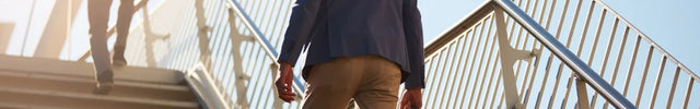 Mann im Business-Outfit geht eine Treppe hinauf – Symbol für Fortschritt, Karriere und persönliche Weiterentwicklung